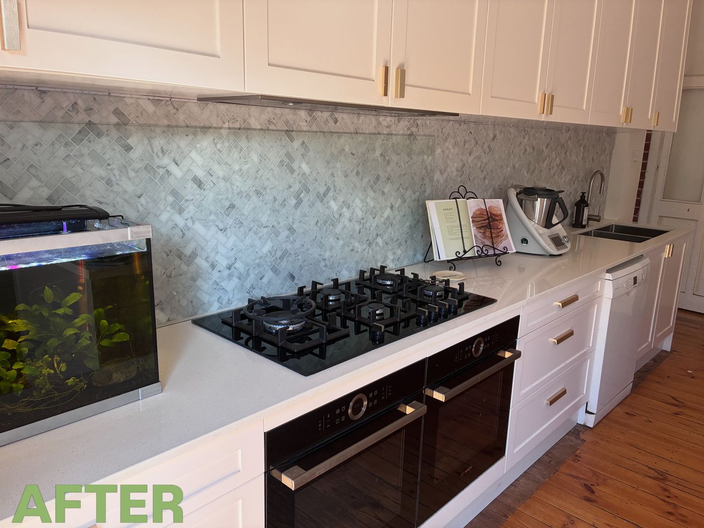 After: the same kitchen with the bench cleared and wiped down, the cooktop clean, and just a recipe book on a stand and the mixer left out.